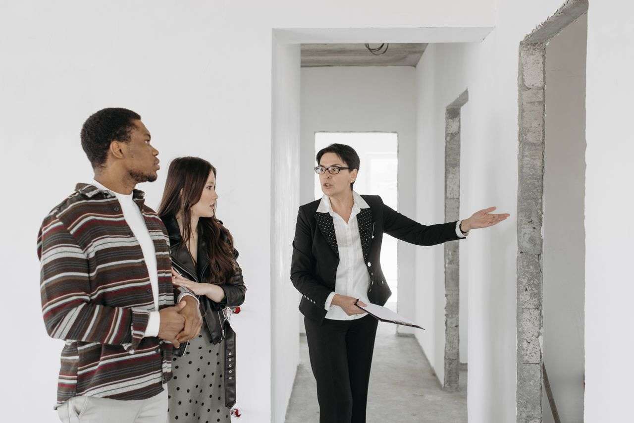Real estate agent shows a house to a couple, discussing features.